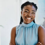Confident young black businesswoman standing at a window in an office alone
